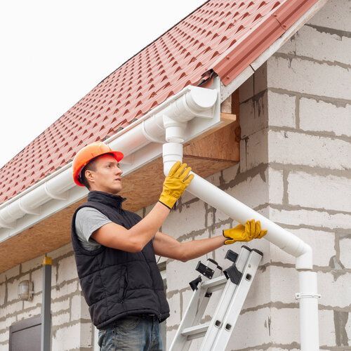construction worker installs the gutter system on the roof